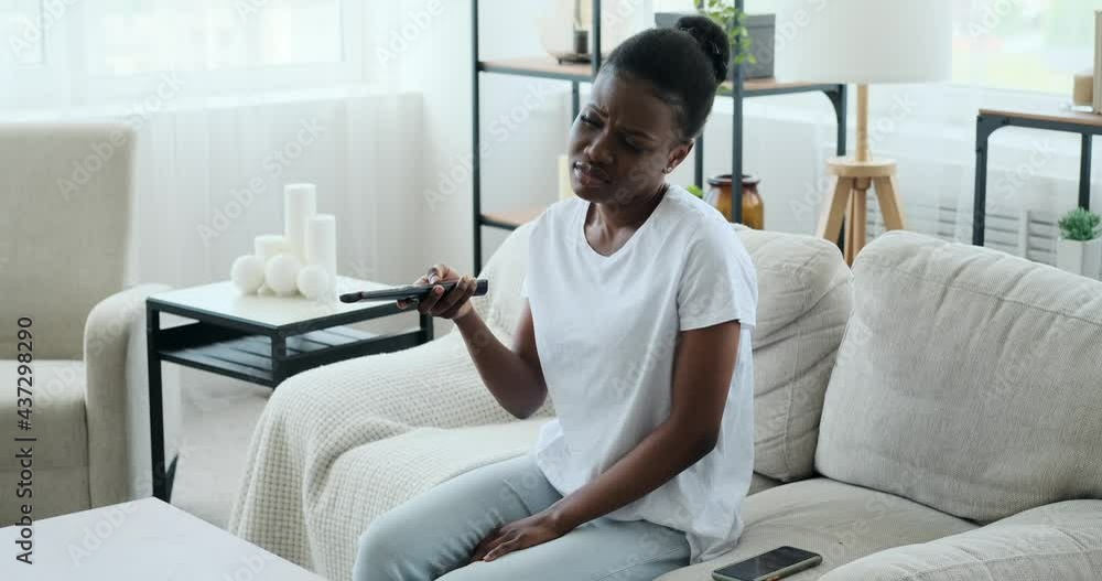 Woman changing channels and watching tv sitting on sofa at home Woman changing channels and watching tv sitting on sofa at home