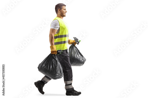 Billede på lærred Full length profile shot of a waste collector in a uniform and gloves carrying b