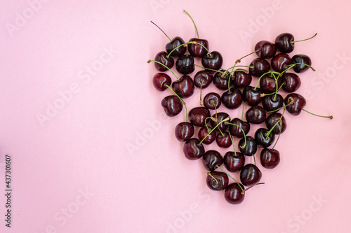 Heart shaped red cherries on a pink background. Cherry background. Sweet cherry isolated on pink background cutout. Copy space