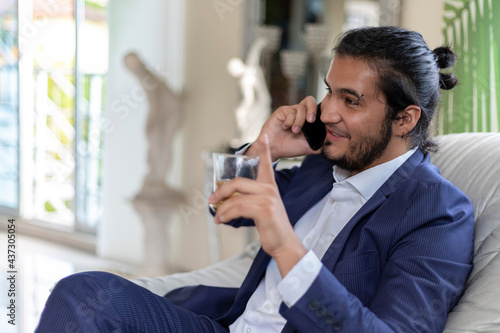 Cheerful young businessman talking on phone in home office