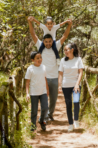 Happy hispanic family walking in the natural park - young parents with their children in the park -latin family