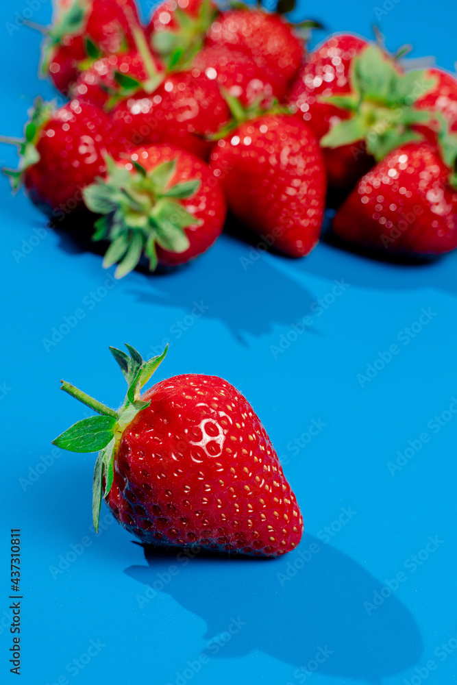 Bunch of strawberries on blue background. Red berry summer seasonal fruit. Bunch of strawberries on blue background. Red berry summer seasonal fruit.