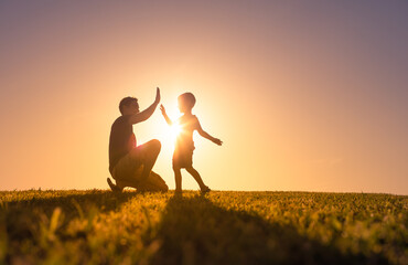 Happy father playing with his son giving him a high five. Father son relationship concept