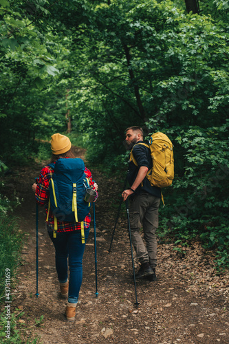 Hikers using trekking poles while wearing backpacks with a camping gear