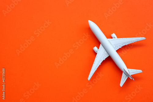 Flat lay design of travel concept with plane on orange background with copy space.