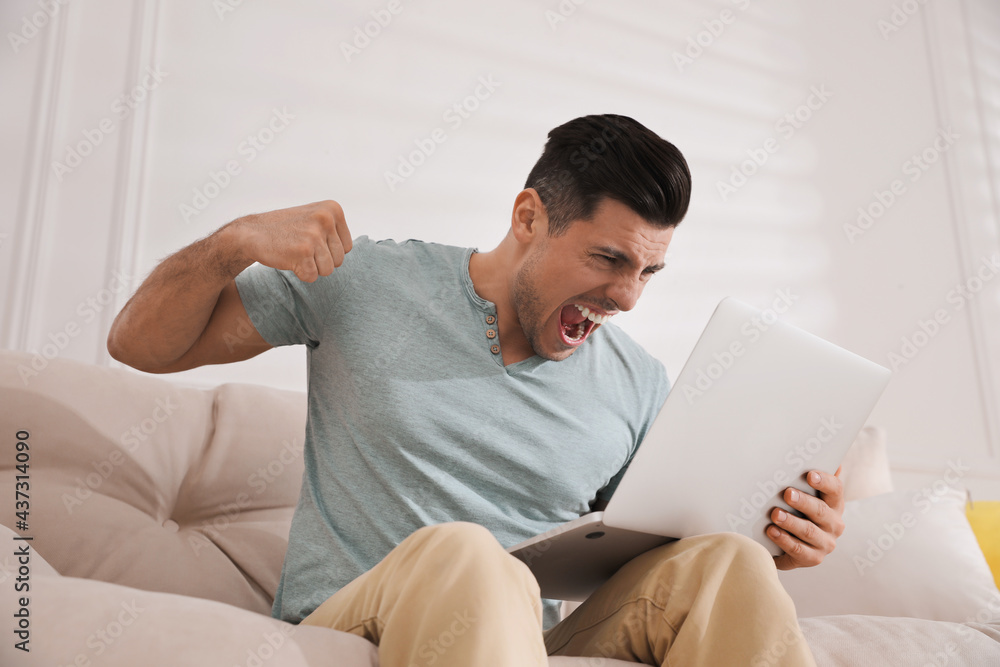 Emotional man working with laptop at home Emotional man working with laptop at home