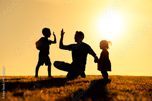 Father interacting playing outdoors with his children giving high five. Parenting and fatherhood concept.  photo