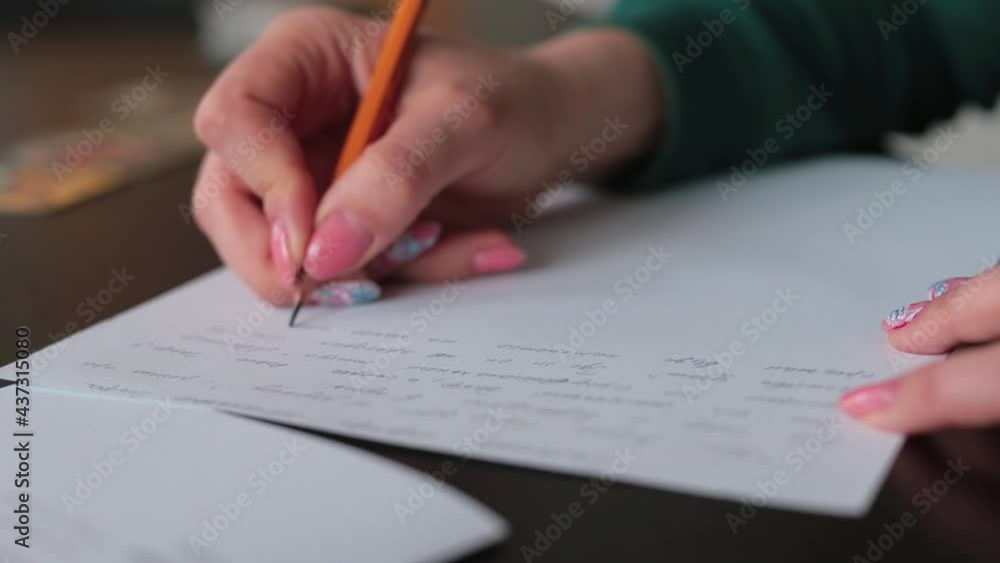 Female hand writes the text in pencil on paper. Formulating thoughts in text form. The use of writing in education. Female hand writes the text in pencil on paper. Formulating thoughts in text form. The use of writing in education.