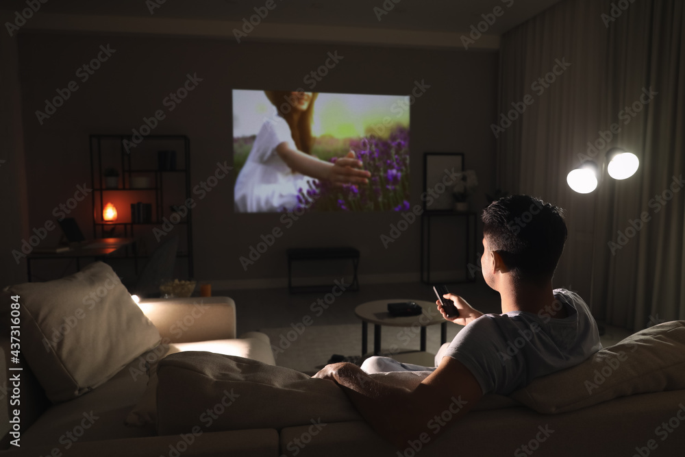 Man watching movie on sofa at night, back view. Space for text foto de  Stock | Adobe Stock