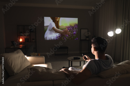 Bild auf Leinwand Man watching movie on sofa at night, back view. Space for text