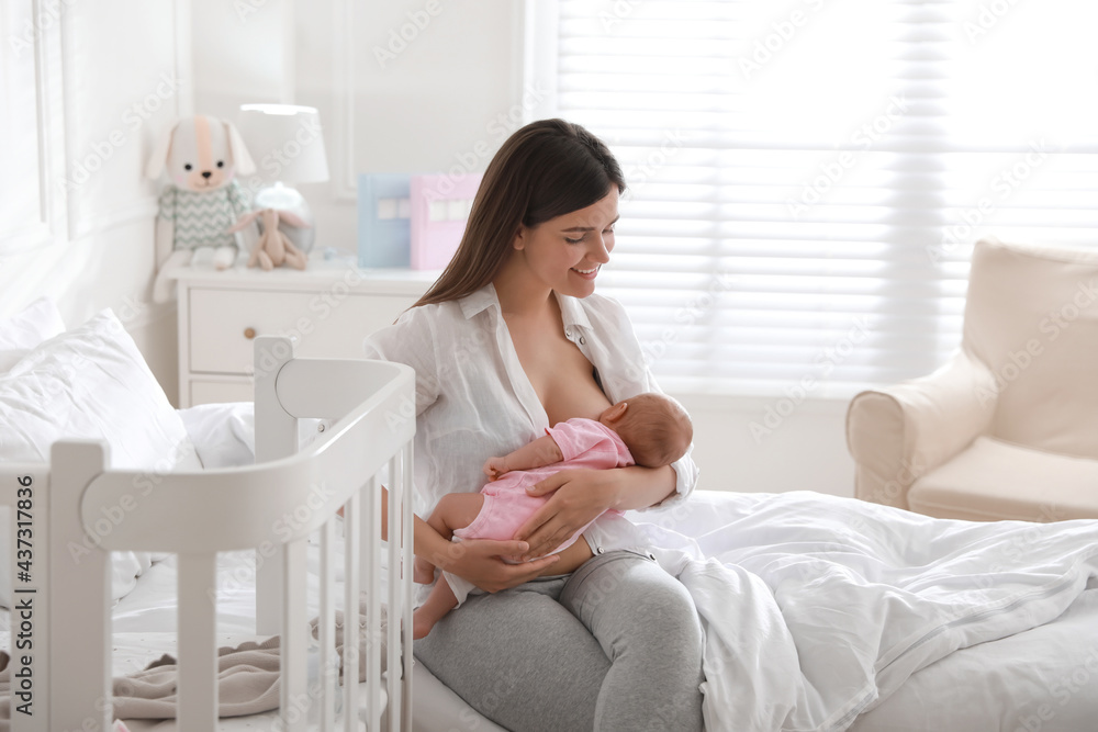 Happy young mother breastfeeding her newborn baby at home