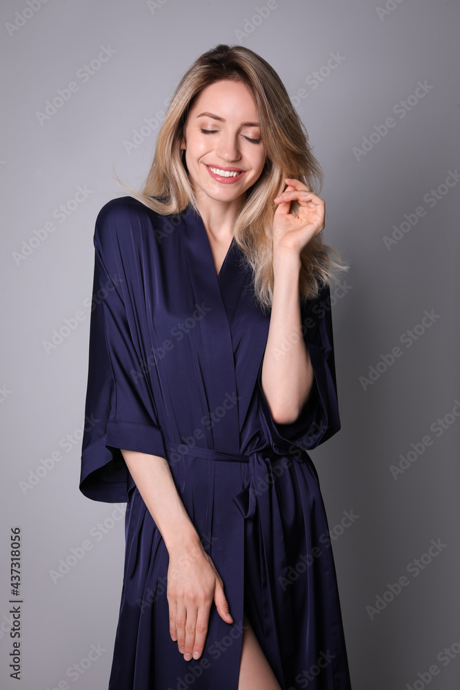 Pretty young woman in beautiful dark blue silk robe on grey background Pretty young woman in beautiful dark blue silk robe on grey background
