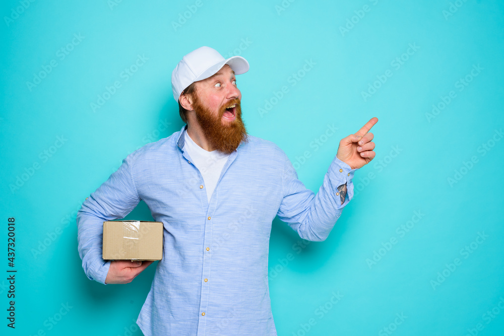 Courier with carton box in hand is surprised and indicates something Courier with carton box in hand is surprised and indicates something