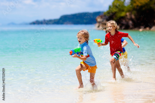 Child with toy water gun. Kids vacation beach fun. photo