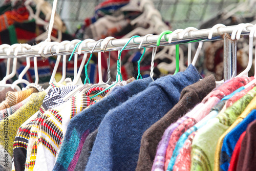 close up of clothing hanging on a rack at resale shop at street fair outside. Used clothing. photo