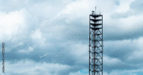 Mobile phone communication radio antenna, 3G, 4G, 5G, 6G. Time Lapse of antenna over fast moving cloudy blue sky at summer. Cellular GSM tower with transmitter. Telecommunication base station network. photo