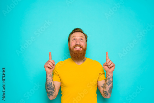 Man with yellow t-shirt and beard is surprised about something photo