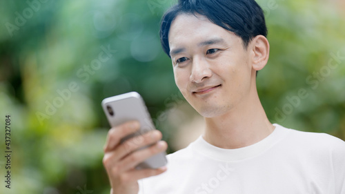 屋外でスマートフォンを使う若い男性