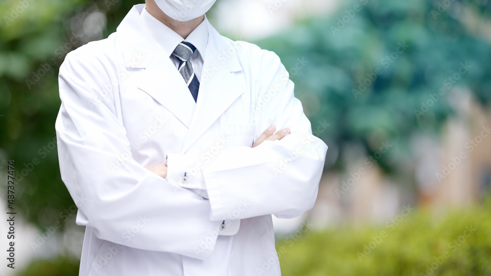 屋外で腕を組む医者