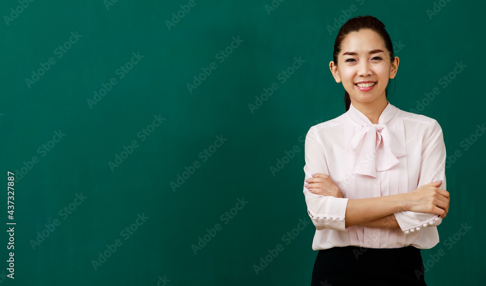 Portrait closeup shot of Asian young female beautiful school teacher tutor professor standing smiling look at camera crossed arms in front of chalkboard in classroom school with blank text copy space