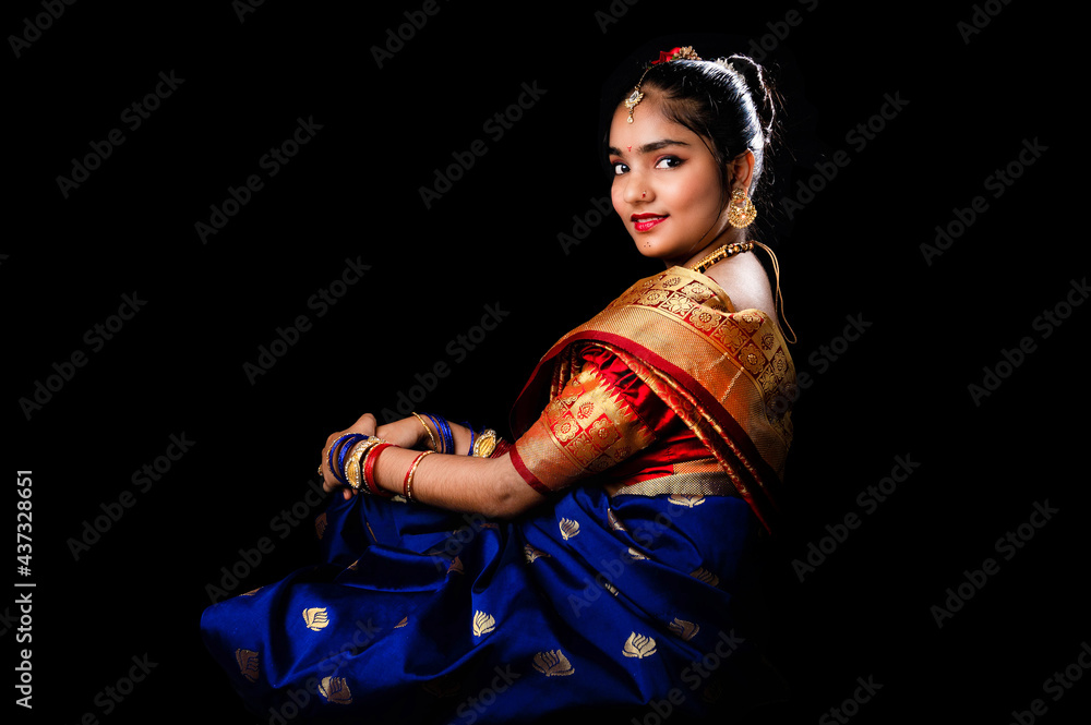 Beautiful Indian girl with clean healthy skin on black background. Wear red and blue Marathi saree.