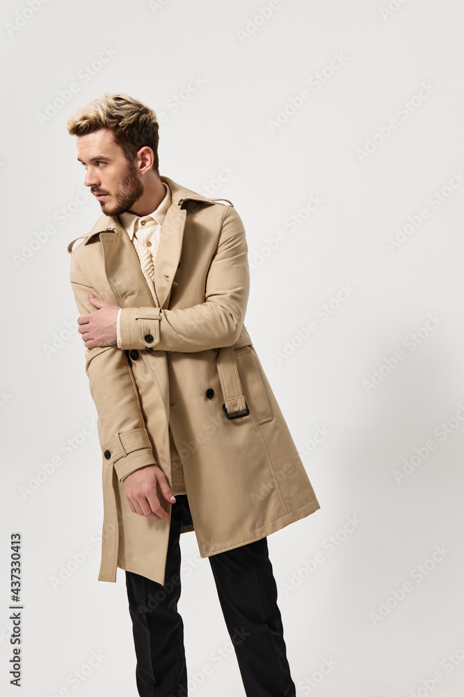 handsome guy in a coat parodies on a light background and looks to the side handsome guy in a coat parodies on a light background and looks to the side