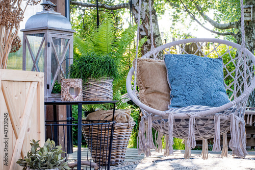 Miejsce wypoczynku w ogrodzie, taras z huśtawką w stylu boho, miejsce na kawę i książkę na świeżym powietrzu