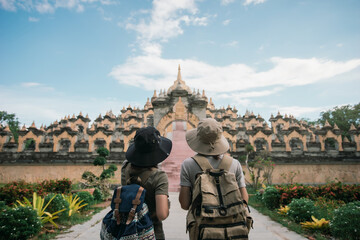 Behind two female traveler wearing a hat with backpack travel in the attraction architecture pagoda of buddhist culture in southeast Asia. Pagoda of Buddhist in Thailand.