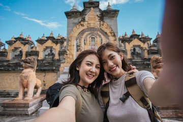 Two Asian woman traveler smile take a photo selfie together with pagoda of buddhist temple in background. Travel pagoda of buddhist in Asia.