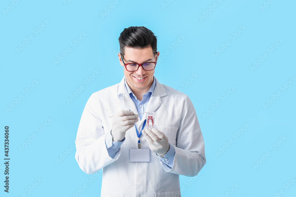 Male dentist with plastic tooth on color background Male dentist with plastic tooth on color background