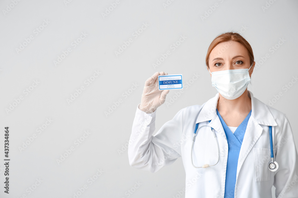 Doctor with International Certificate of Vaccination on grey background Doctor with International Certificate of Vaccination on grey background