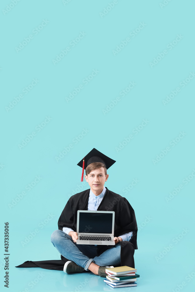 Male graduating student with laptop on color background Male graduating student with laptop on color background