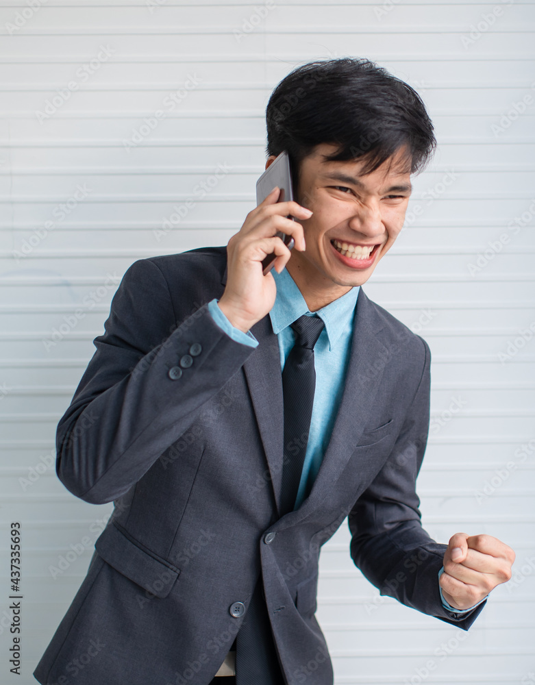 Asian businessman speaking on smartphone and celebrating success Asian businessman speaking on smartphone and celebrating success