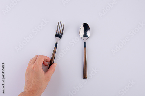 Hand and silver spoon isolated on white background