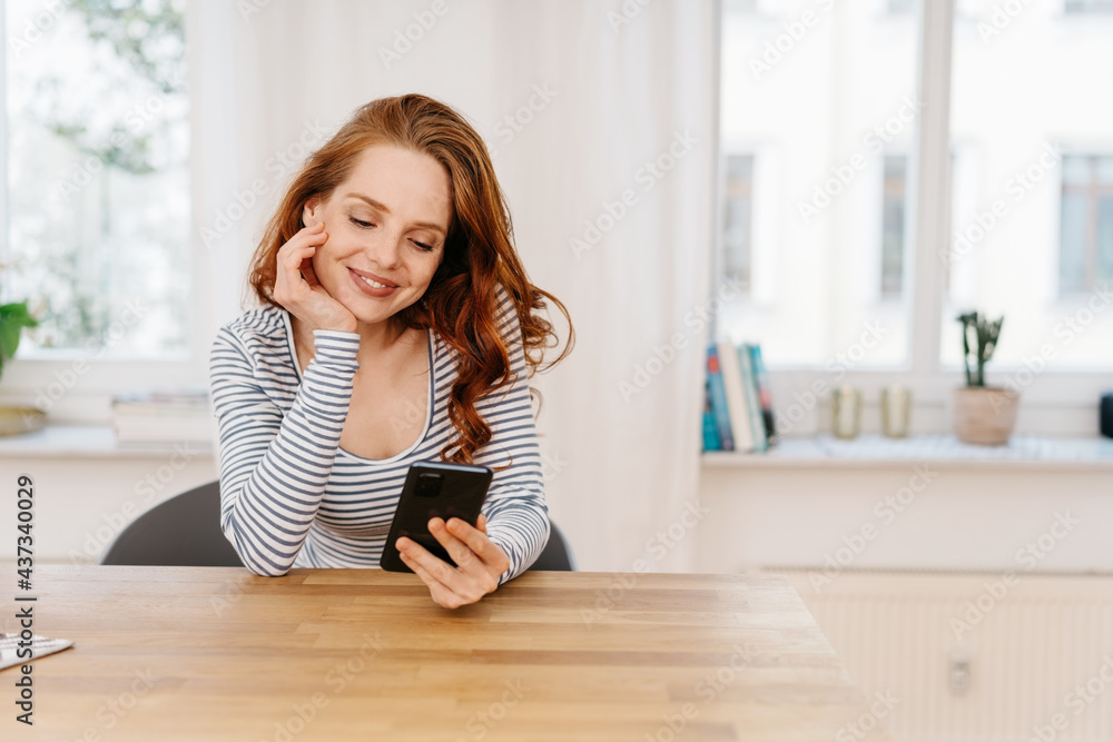 Young woman smiling sweetly as she watches media on her mobile Young woman smiling sweetly as she watches media on her mobile