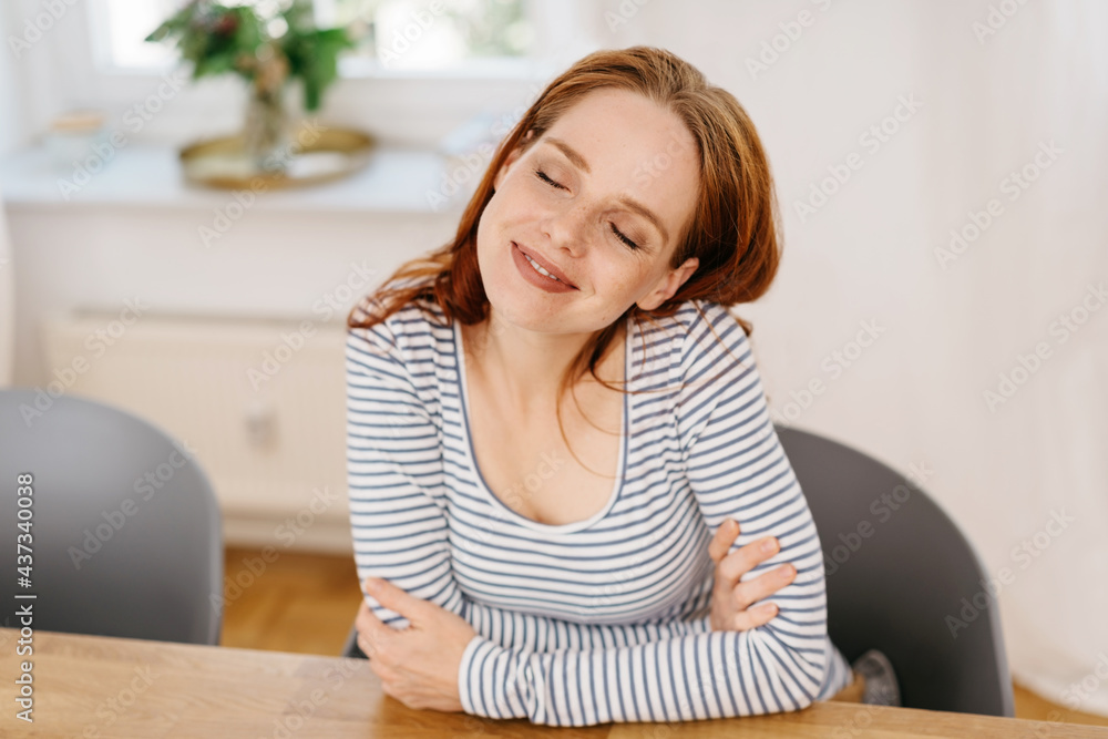 Blissful young woman sitting daydreaming with a smile Blissful young woman sitting daydreaming with a smile