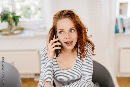 Fotografie Young woman listening in excited fascination to a call
