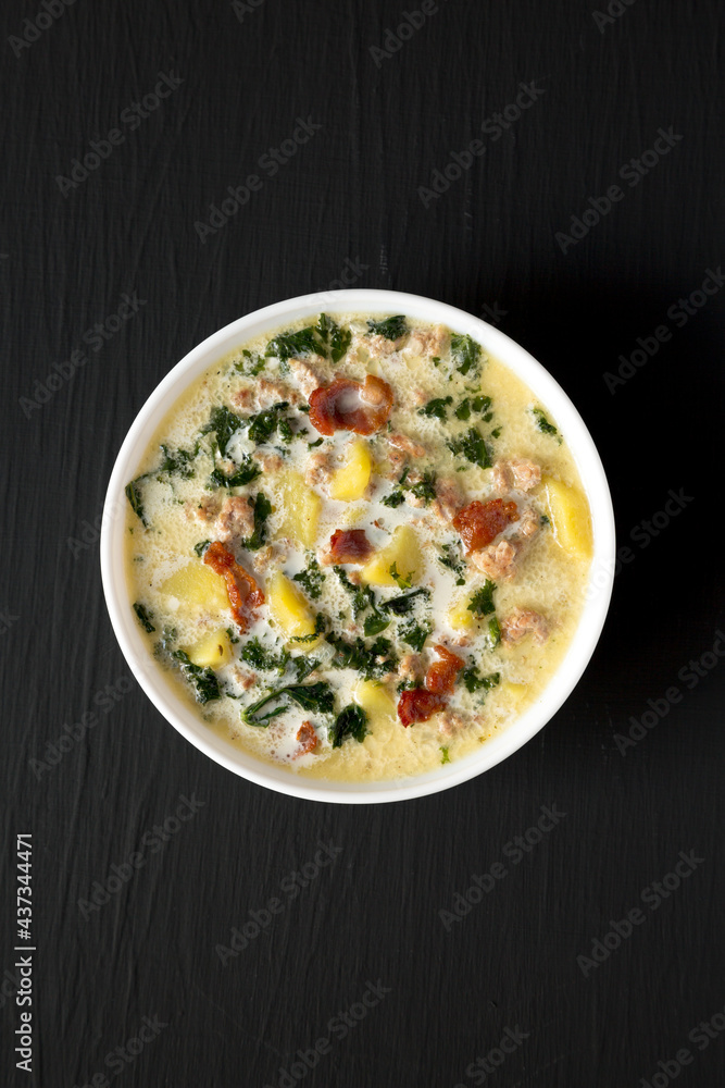 Homemade Zuppa Toscana with Kale and Bread in a white bowl on a black background, top view. Overhead, from above, flat lay. Homemade Zuppa Toscana with Kale and Bread in a white bowl on a black background, top view. Overhead, from above, flat lay.