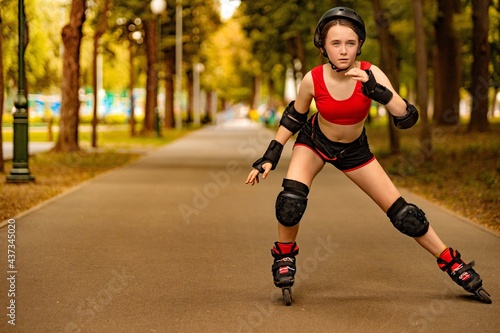 Roller skating girl kid in park rollerblading on inline skates. Caucasian young woman in outdoor activities.