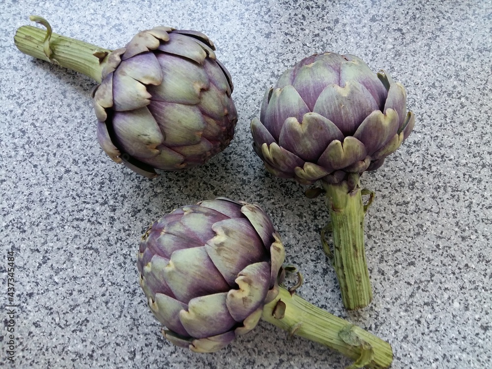 Obraz premium three purple artichokes displayed on a table