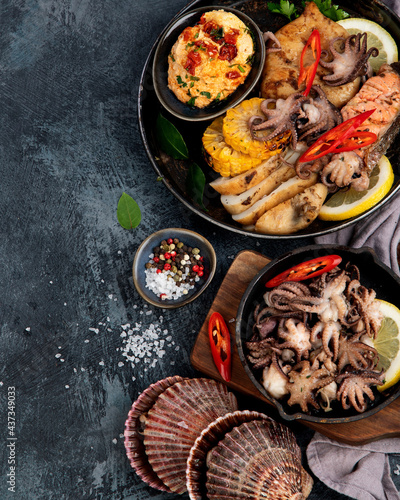 Grilled seafood variety with vegetables on dark background.