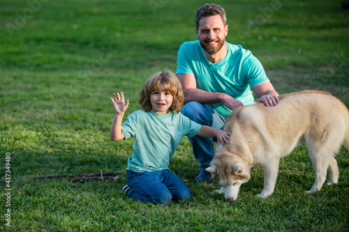 Beautiful happy family is having fun with dog husky. Happy father and his son playing with dog in park.