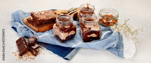 Trifles made with chocholate mousse and brownie on light gray background.