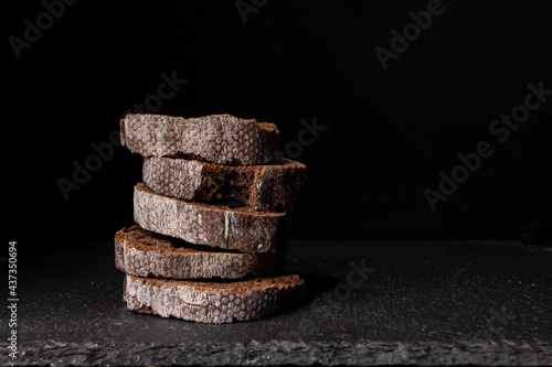 Rye bread without yeast on a black background. Three slices of sliced bread with crumbs. Place for text. Banner for a design project. photo