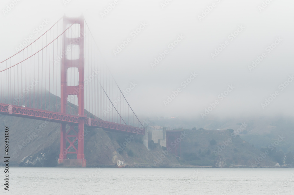 Fototapeta premium The red structure of the golden gate bridge in the fog, San Francisco, California, USA. White sky, with copy-space.