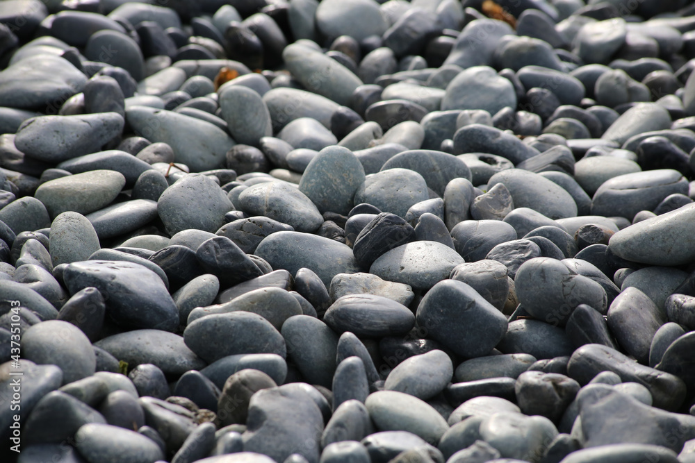 Obraz premium Round stones on a dry river bed outside in nature. Smooth pebbles with light gray tones in ambient light.