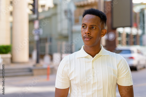 Portrait of young African businessman wearing casual clothes at city street while thinking
