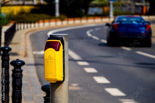 Pedestrian crossing button with blurred car on a road