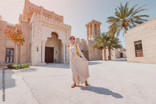 Photography Woman tourist wearing red turban and biege long dress walks through the old narrow streets of Bur Dubai and Creek