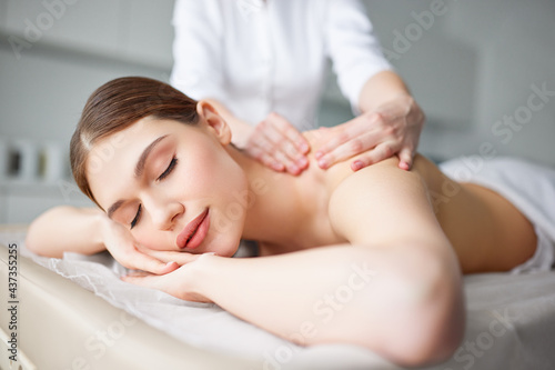 Young woman enjoying classic back massage by professional female therapist or masseur
